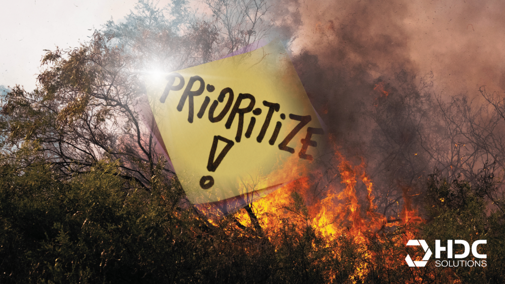 Waldbrand als Symbol für Krisensituation mit dem Wort „Prioritize“ auf Notizzettel – visuelle Metapher für Priorisierung im Ernstfall